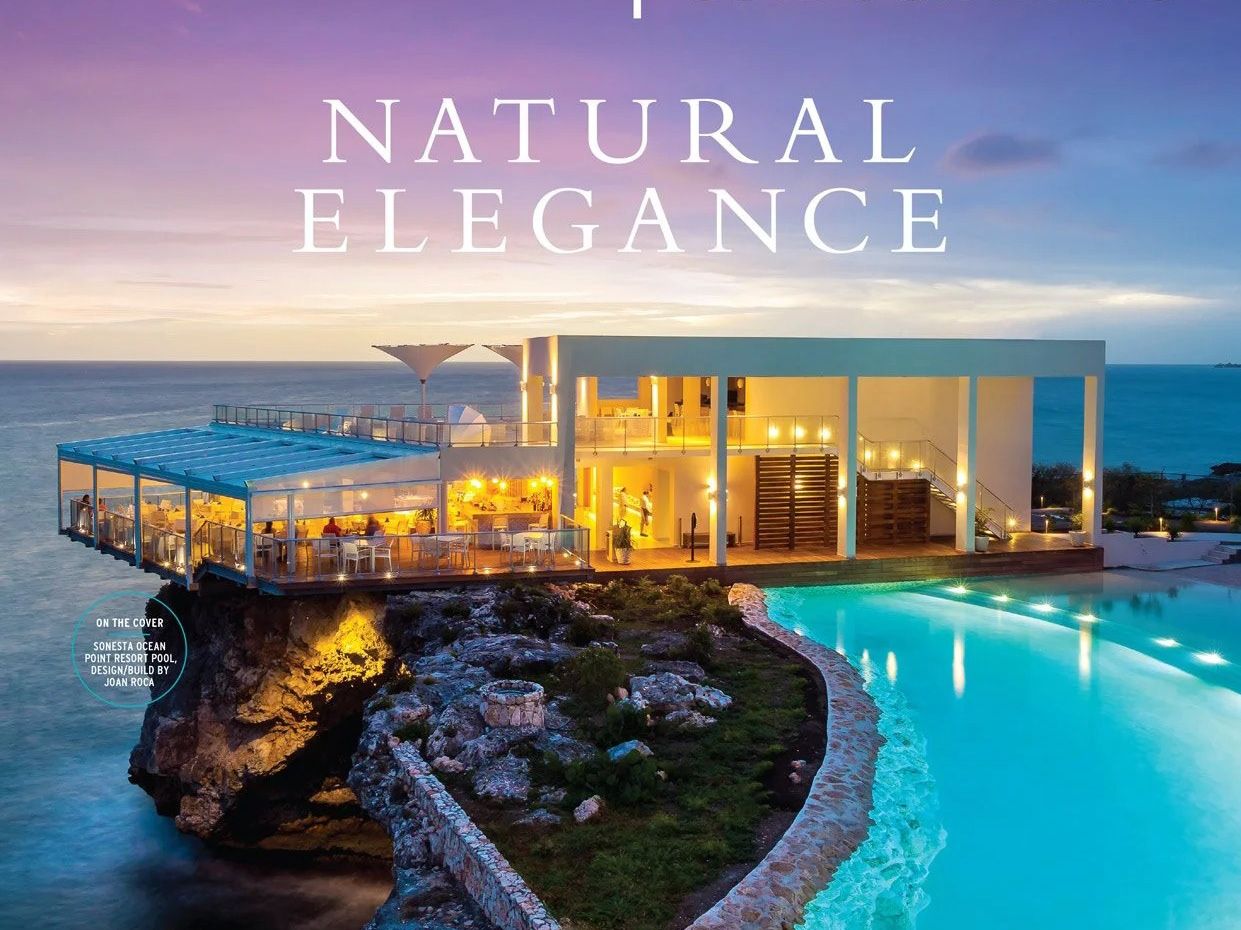 Clifftop resort at twilight — a lit restaurant pavilion above an infinity pool over the sea.